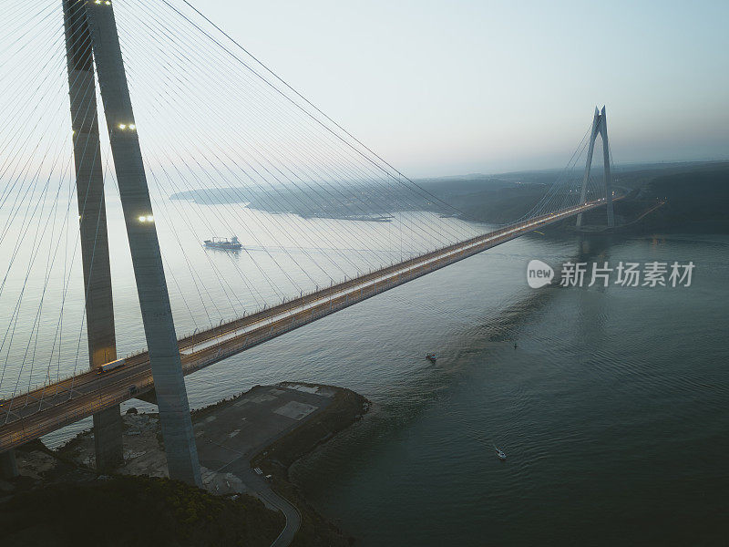 伊斯坦布尔雾蒙蒙的早晨:日出时分，货船从Yavuz Sultan Selim大桥下通过